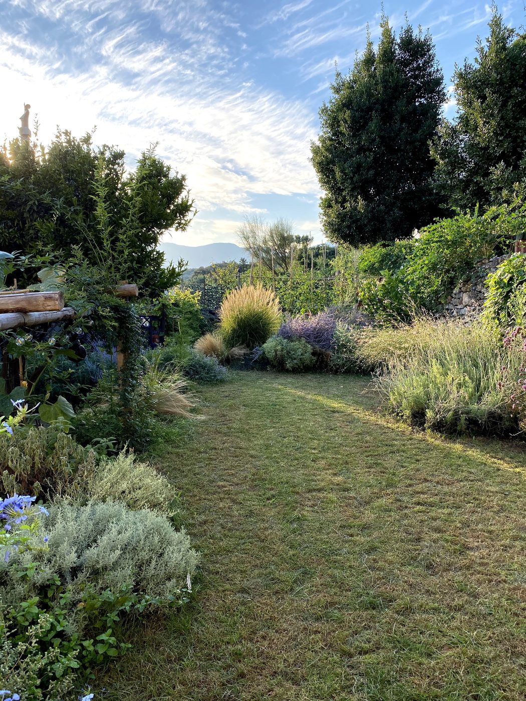 Private lawn garden at Ca' Remurin with Mediterranean plants and open views over the Verezzi hills, Liguria