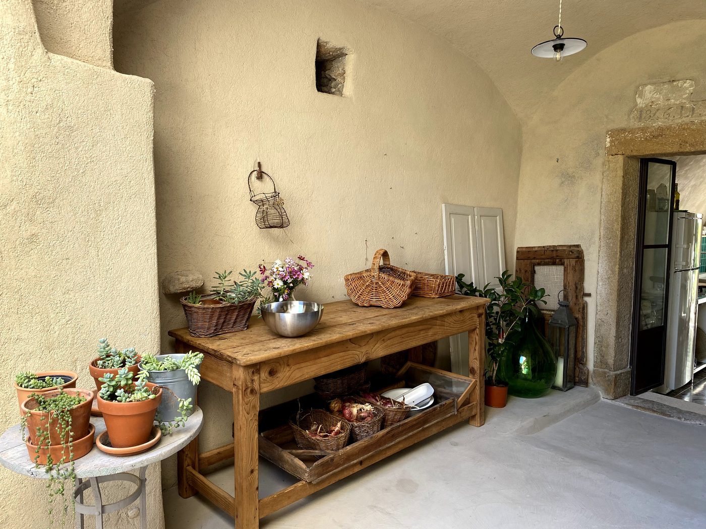 Covered stone entrance at Ca' Remurin, Verezzi, with a vaulted ceiling and rustic wooden table